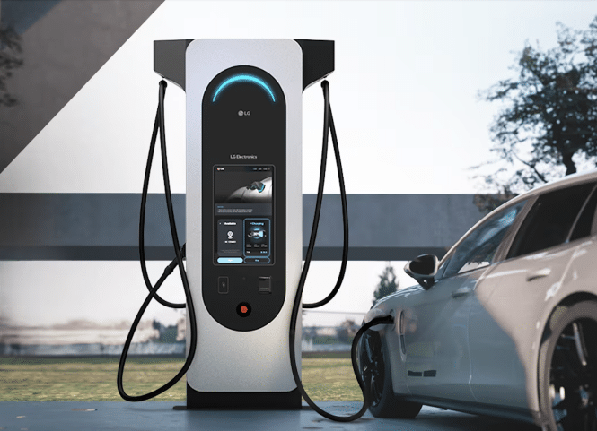 A modern EV charging station with a sleek design and digital display is connected to a white car. Situated outdoors with trees in the background, this station, akin to vital healthcare for vehicles, features multiple charging cables for efficient energy replenishment.
