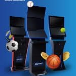 Three EasyPay self-service sports betting kiosks are shown, surrounded by sports balls and gold coins on a blue background. The text reads EasyPay Kiosk Solutions and EasyBet Betting Made Easy. Romanian flag and logo are visible.
