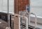 An automated TSA CLEAR Plus e-gate with a facial recognition screen stands in a modern, bright room with large windows, brick walls, and views of a river and cityscape—typical of advanced security found in U.S. airports.