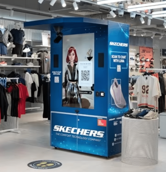 A blue Skechers AI Kiosk with a large touchscreen display shows a virtual assistant in a clothing store at shopping malls. QR codes and shoes are visible, with racks of clothes and mannequins in the background.
