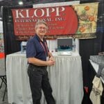 John Oder discusses coin and currency handling equipment at the Klopp International Inc. exhibit.