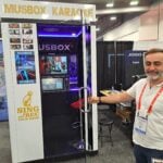 Mark Brut invites attendees to enter the mobile karaoke kiosk at the Musbox exhibit.