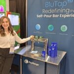 Sarah White shows the BluTap self-pour technology at the PayRange LLC exhibit.