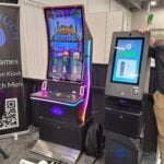 Ryan Ribeau shows the Vortex redemption kiosk and its 43-inch curved capacitive touchscreen gaming cabinet at the Rite Touch Distribution exhibit.